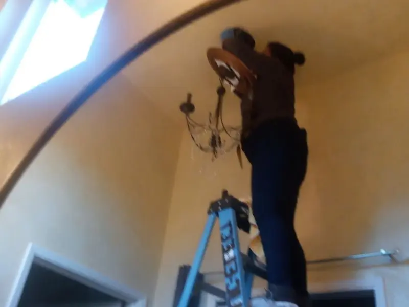 Electrician installing a chandelier in a Central Park residence